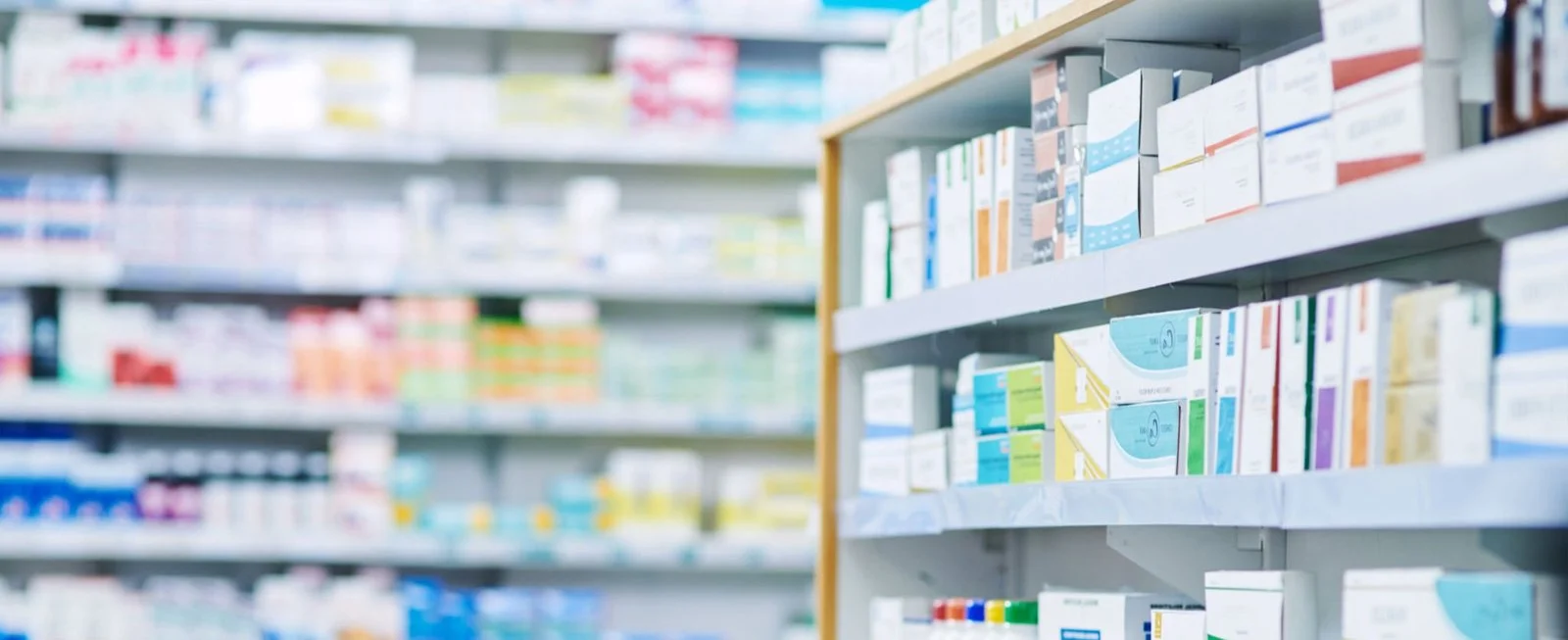 Shelves of packaged medicines in a UK pharmacy dispensary